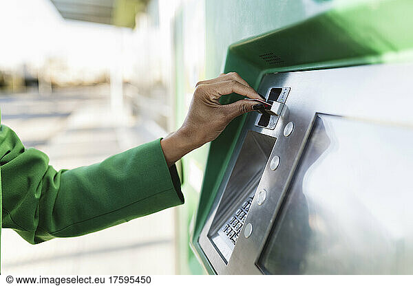 Businesswoman's hand inserting smart card in ticket machine