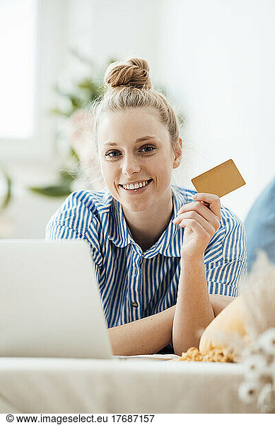 Businesswoman showing credit card lying down at home