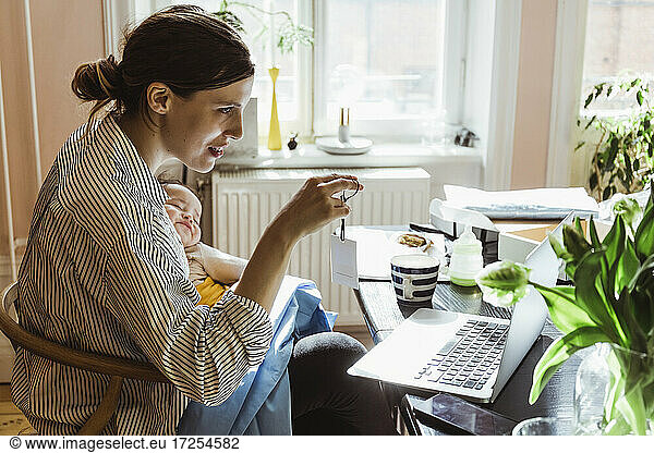 Businesswoman showing label on video call through laptop at home office