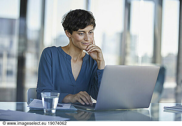 Businesswoman sitting at desk in office using laptop