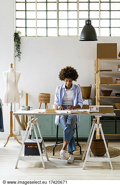 Businesswoman sitting at desk while working at studio