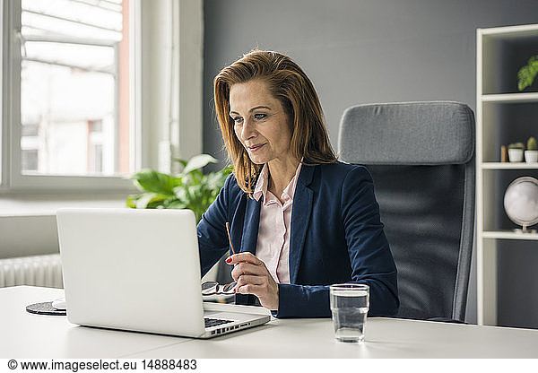 Businesswoman sitting in office working on laptop