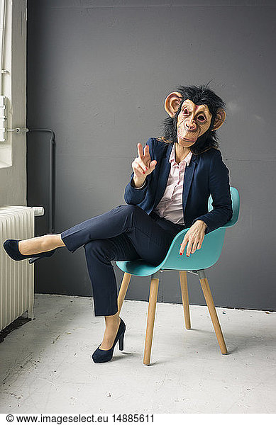 Businesswoman sitting on chair  wearing monkey mask  gesturing