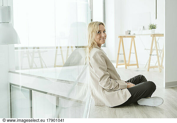 Businesswoman sitting on the floor in office corridor