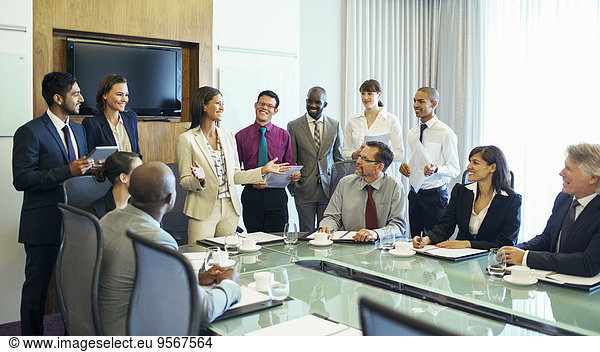 Businesswoman standing at head of conference table and talking