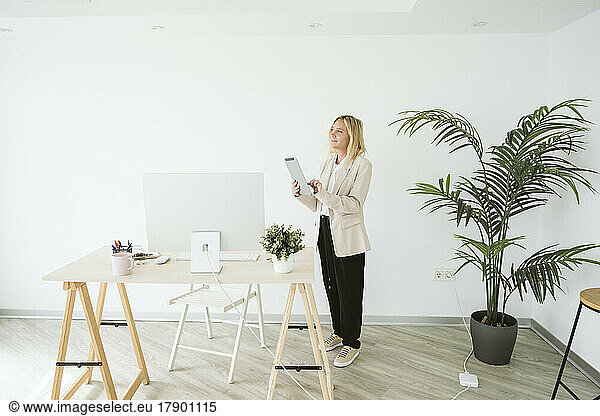 Businesswoman standing in office using tablet PC