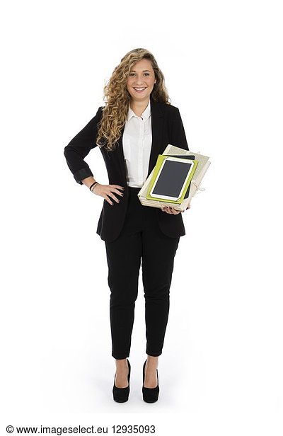 Businesswoman standing in the studio with tablet and documents in her arms  she is wearing a black suit and a white shirt.