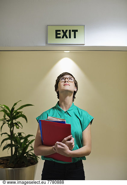 Businesswoman standing under office ‘exit’ sign