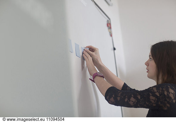 Businesswoman sticking adhesive notes in office