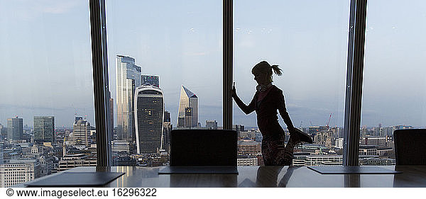 Businesswoman stretching at highrise office window  London  UK