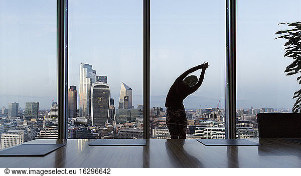 Businesswoman stretching at highrise office window  London  UK