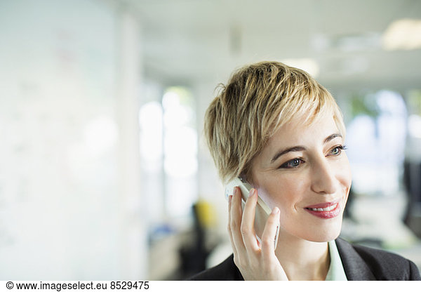 Businesswoman talking on cell phone in office