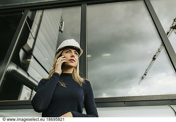 Businesswoman talking on mobile phone in front of window