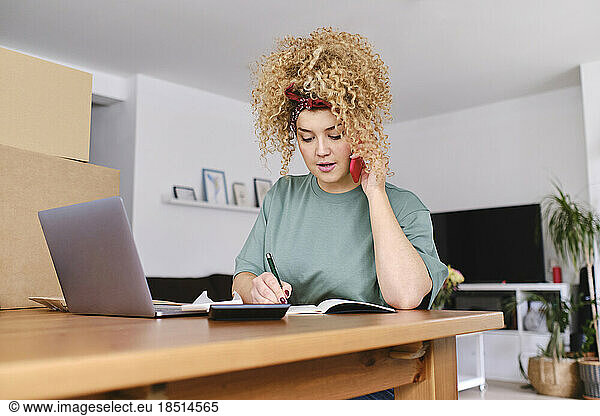 Businesswoman talking on smart phone at desk