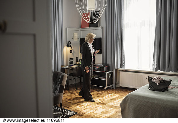 Businesswoman talking on smart phone while walking in hotel room