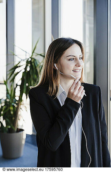 Businesswoman talking on wired headphones in office