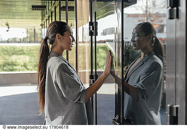 Businesswoman touching reflection on glass door