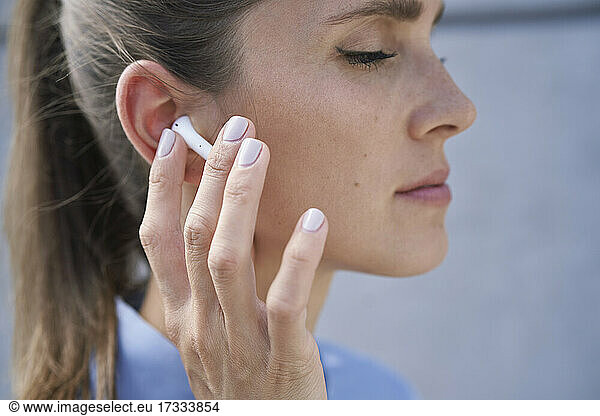 Businesswoman touching wireless in-ear headphones