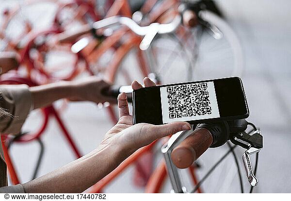 Businesswoman unlocking bicycle through smart phone at parking station