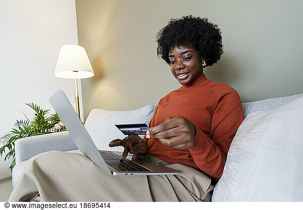 Businesswoman using credit card and paying through laptop at home