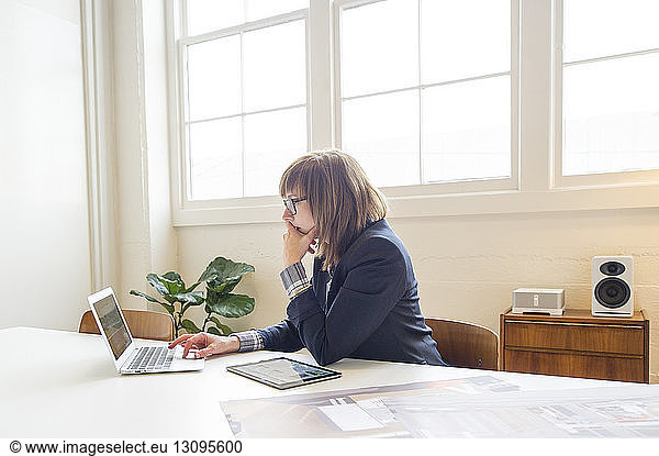 Businesswoman using laptop computer while sitting at desk in office
