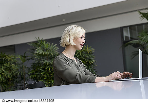 Businesswoman using laptop in bright office building
