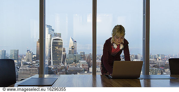 Businesswoman using laptop in highrise office  London  UK