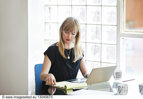Businesswoman using laptop on table in creative office