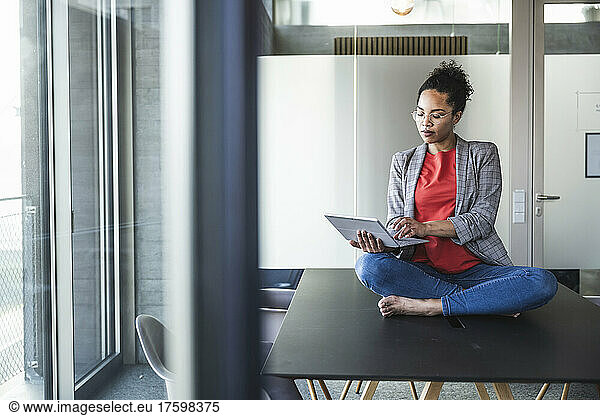 Businesswoman using laptop sitting on desk at work place