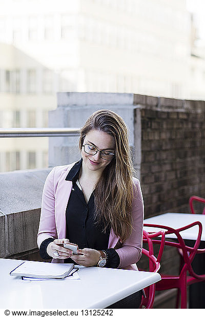 Businesswoman using mobile phone while sitting in balcony