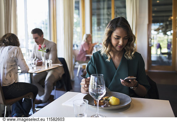 Businesswoman using mobile phone while sitting in restaurant