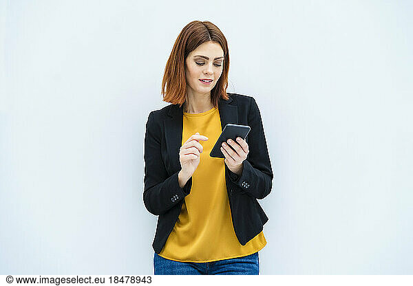 Businesswoman using smart phone against white background