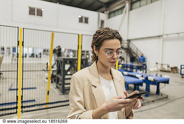 Businesswoman using smart phone in industry