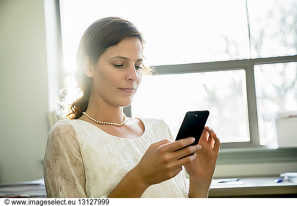 Businesswoman using smart phone while sitting in office
