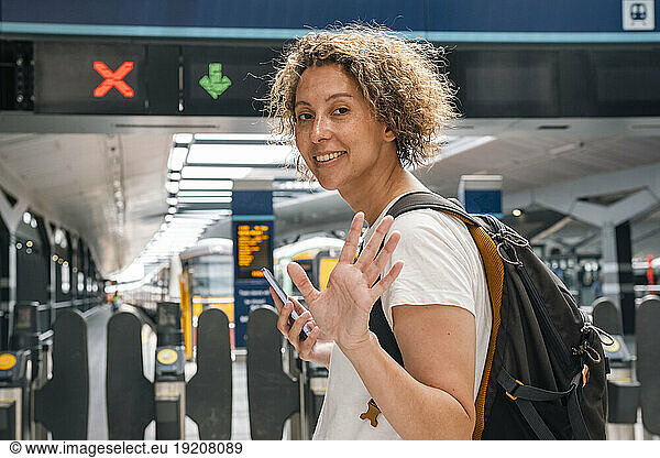 Businesswoman waving at railroad station