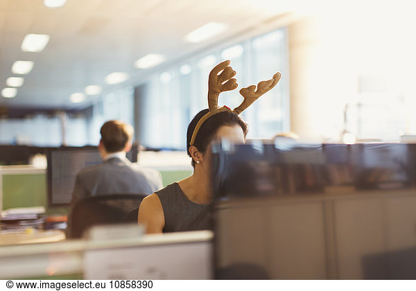 Businesswoman wearing antler headband in office