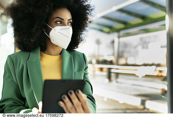 Businesswoman wearing protective face with tablet PC at station