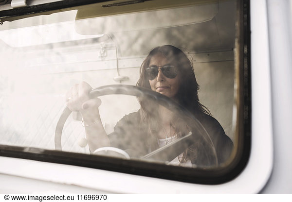 Businesswoman wearing sunglasses while driving portable office truck