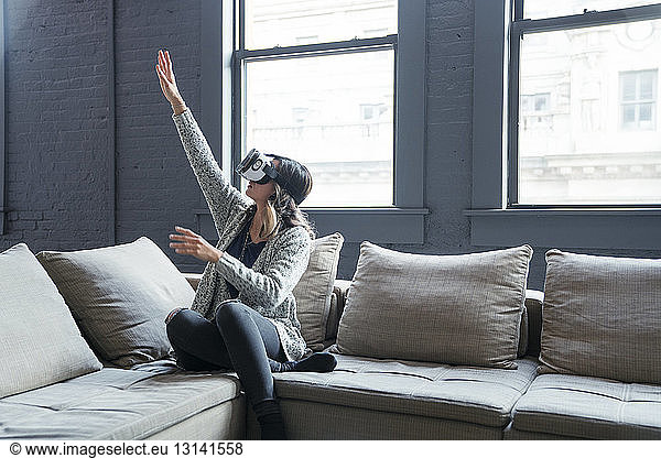 Businesswoman wearing virtual reality simulator gesturing in office