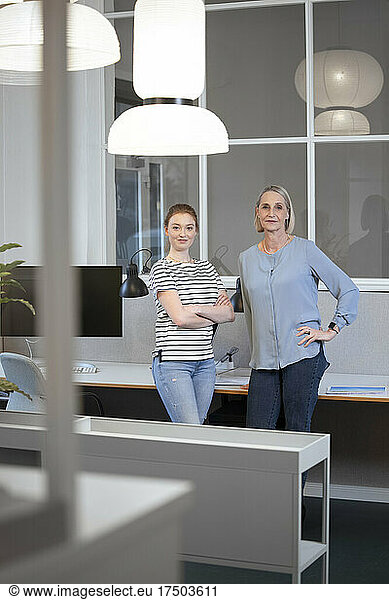 Businesswoman with arms crossed standing by colleague in office