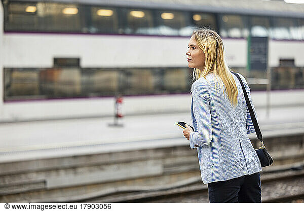 Businesswoman with blond hair waiting for train at station