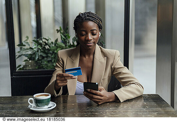 Businesswoman with credit card and smart phone sitting at cafe
