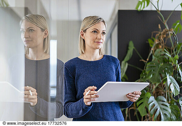 Businesswoman with digital tablet in office thinking
