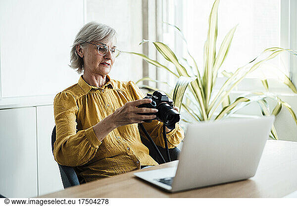 Businesswoman with eyeglasses checking camera in office