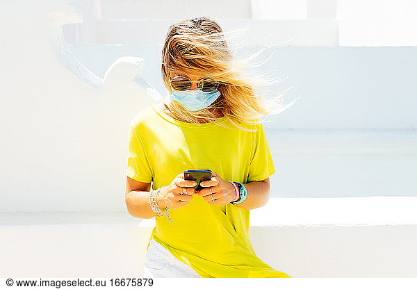 Businesswoman with face mask working using phone