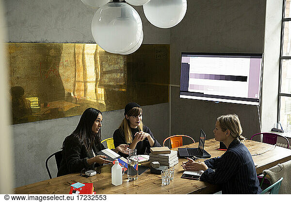 Businesswoman with female colleagues discussing over color swatch in conference room