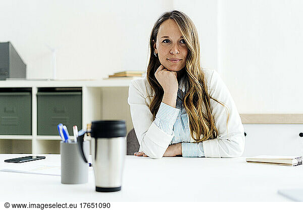 Businesswoman with hand on chin at desk in office