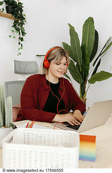 Businesswoman with headphones working on laptop at creative office