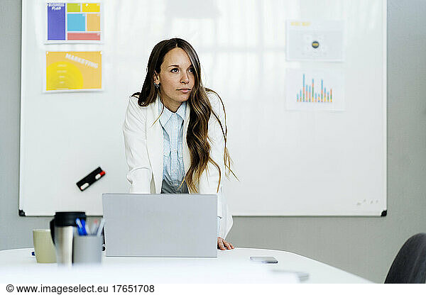 Businesswoman with laptop at desk in office