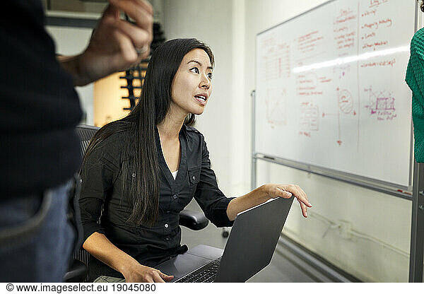 Businesswoman with laptop computer talking while sitting in meeting